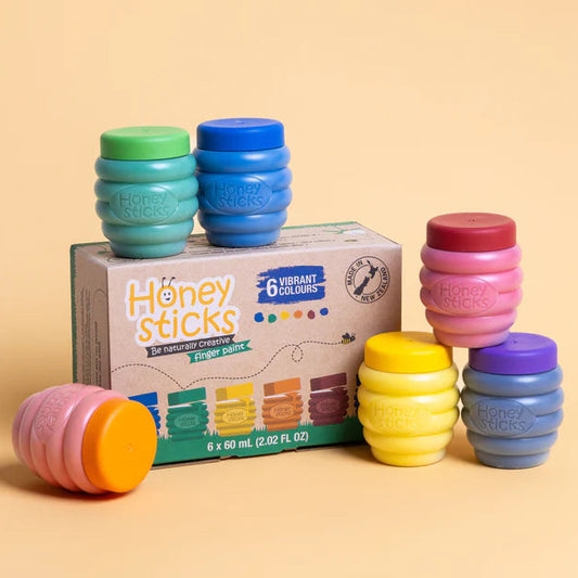 Colorful honey sticks finger paints with a box labeled 'Honey Sticks' on a beige background