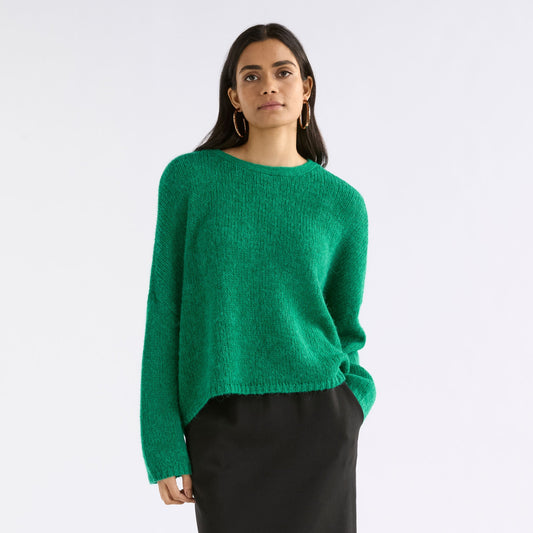 Woman wearing a green sweater and black skirt on a white background